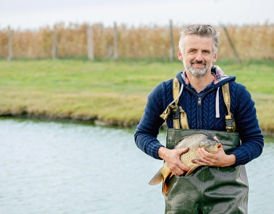 Fischer Robert Jungwirth am Teich mit Karpfen in der Hand.