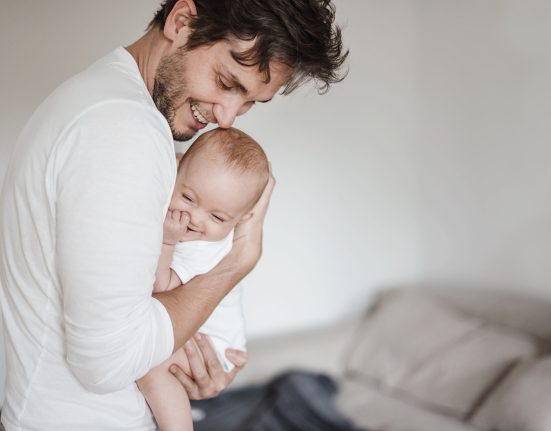 Lächelnder Vater hält lachendes Baby im Arm.