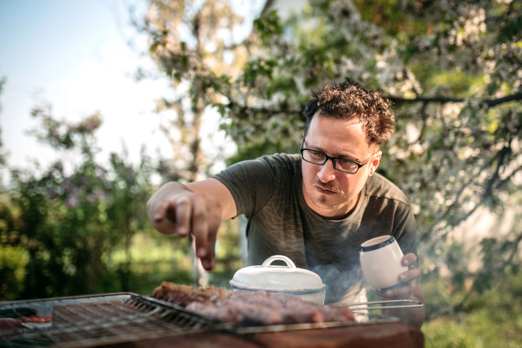Mann salzt sein Steak am Griller