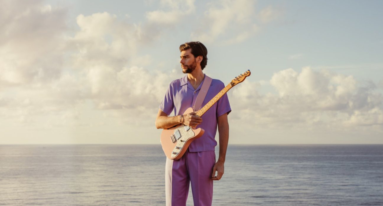 Sänger Alvaro Soler mit einer Gitarre auf einem Boot auf stehendem Gewässer im Hintergrund