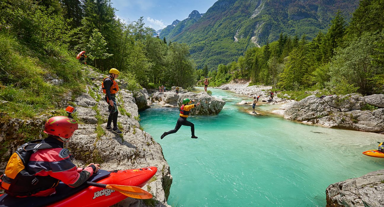 Ein Mann springt von einem Felsen in den Fluss Soča