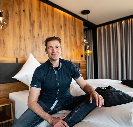 Erich Scheiblhofer entspannt auf einem der Betten im Resort sitzend.