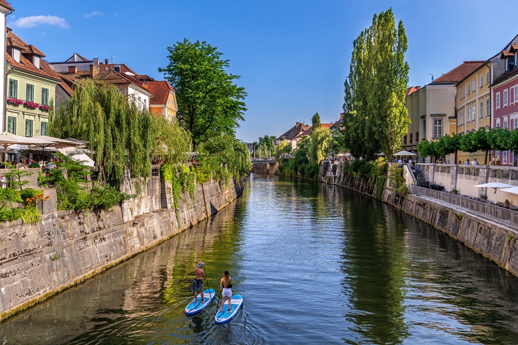 Zwei Stand-Up-Paddler auf dem Fluss Ljubljanica mitten in der Hauptstadt Sloweniens