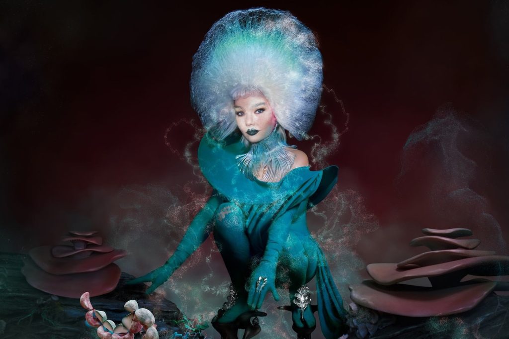Björk in einem türkisen Pilz-Kostüm, umgeben von Pilzen. © m/m (paris) and futuredeluxe