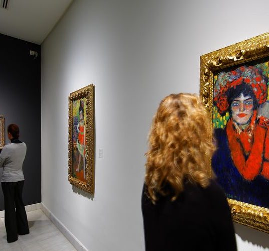 Eine Frau betrachtet ein Bild von Pablo Picasso an der Wand.