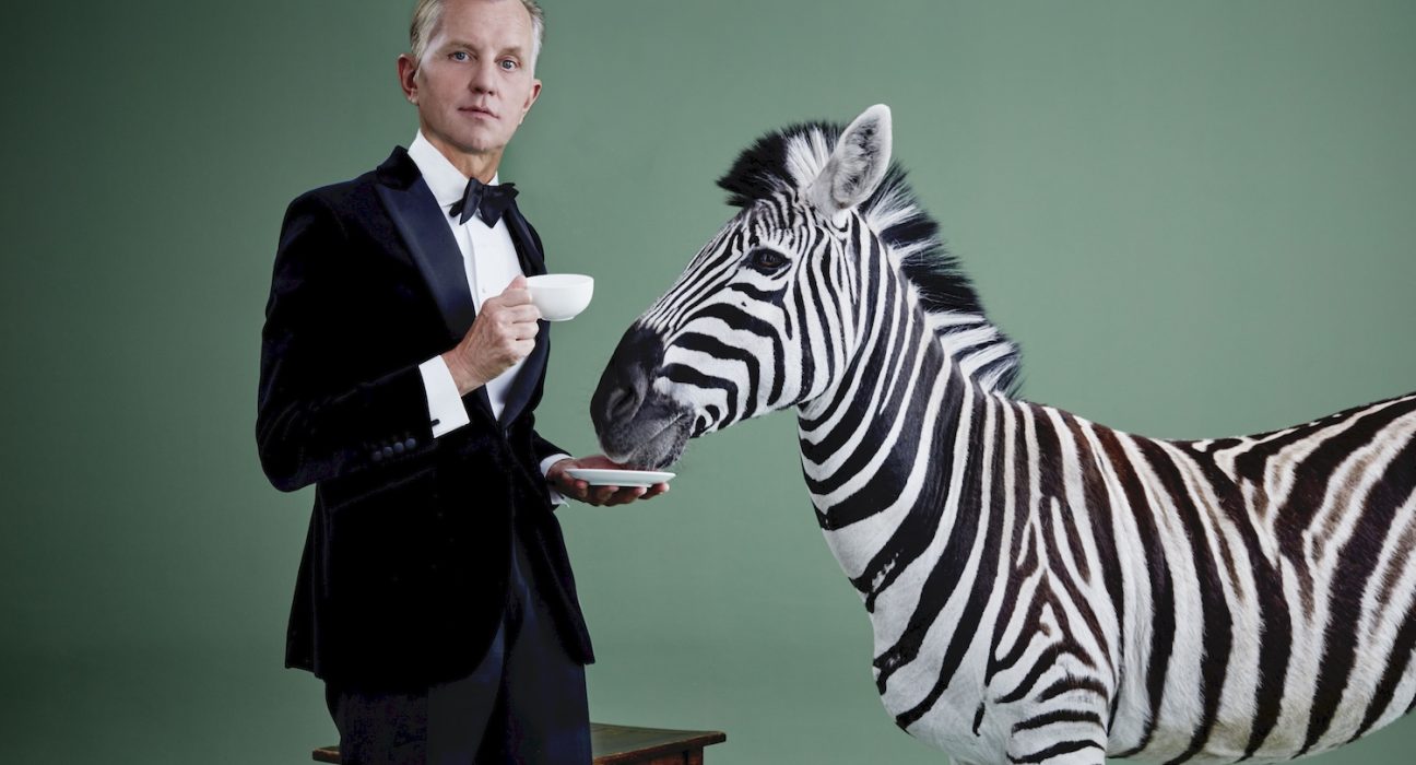 Max Raabe im Anzug mit einer Tasse Tee, neben ihm ein Zebra mit dem Maul in der Untertasse.