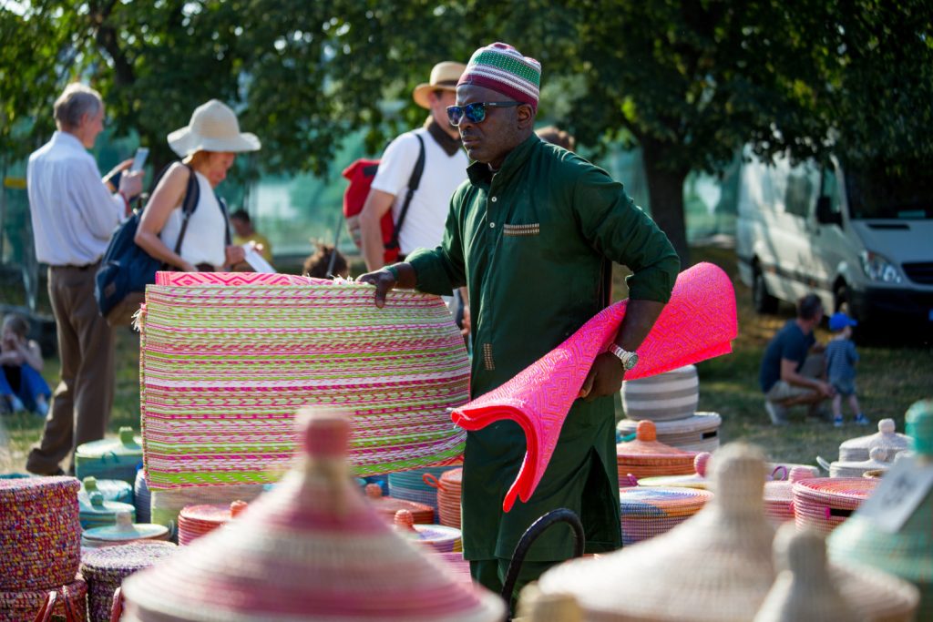 Mann mit Hut trägt einen pinken Teppich in der Hand