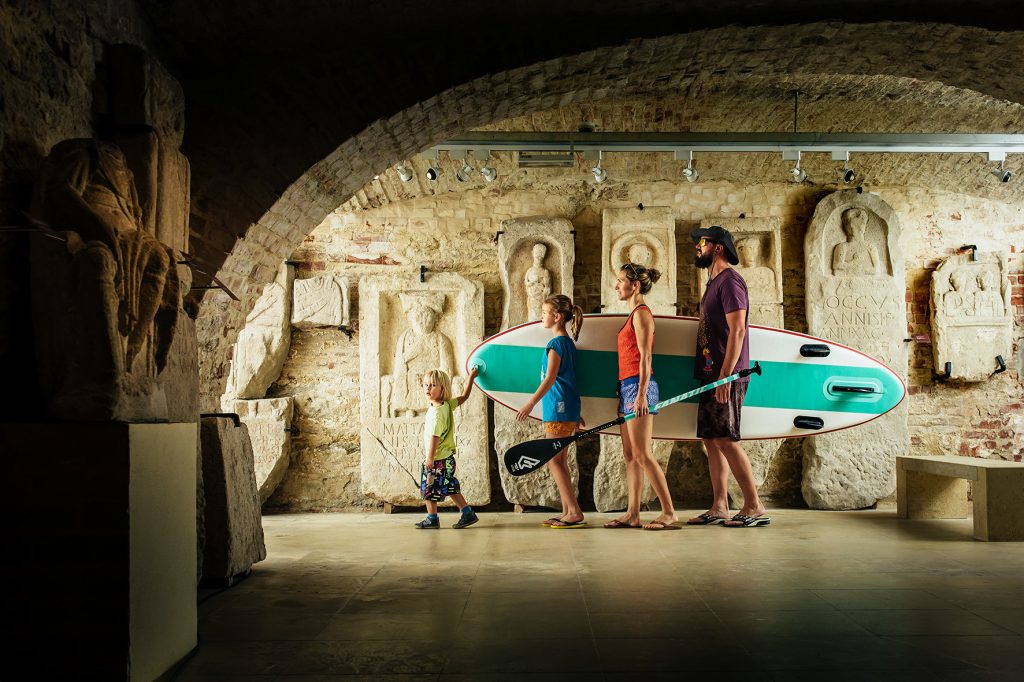 Familie mit Surfboard im Lapidarium 1 des Landesmuseum Burgenland