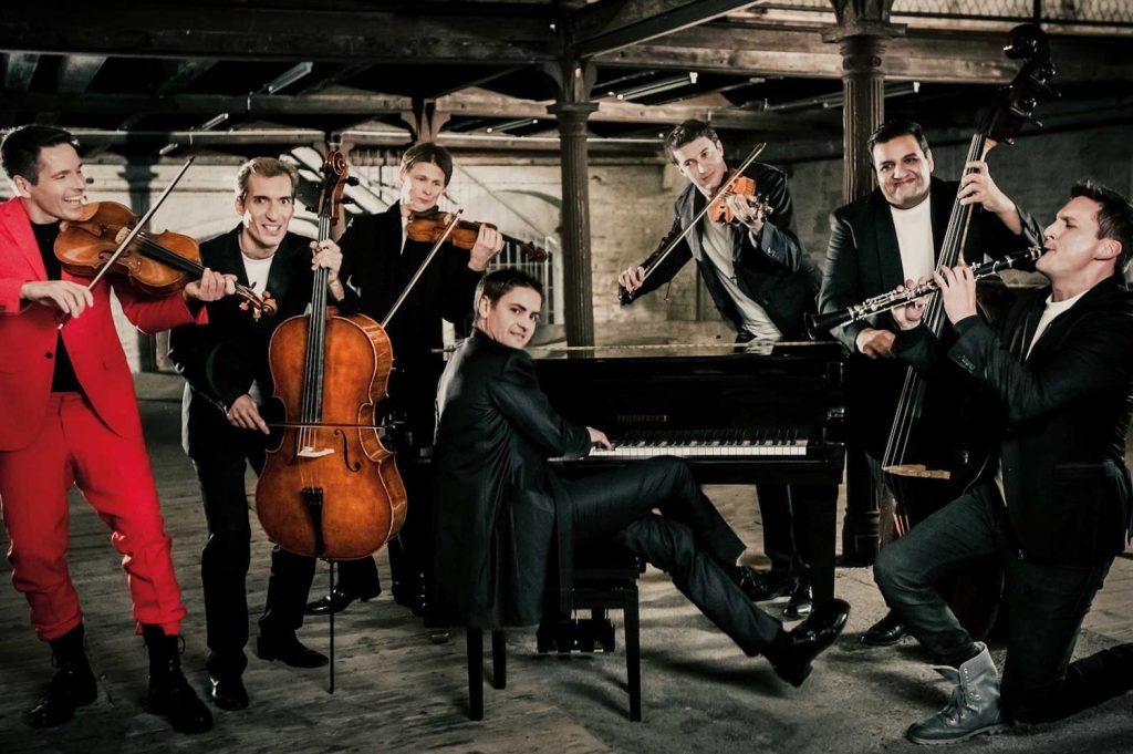 Sieben Musiker (Philharmonix) mit ihren Instrumenten in einer alten Fabrikshalle © Max Parovsky
