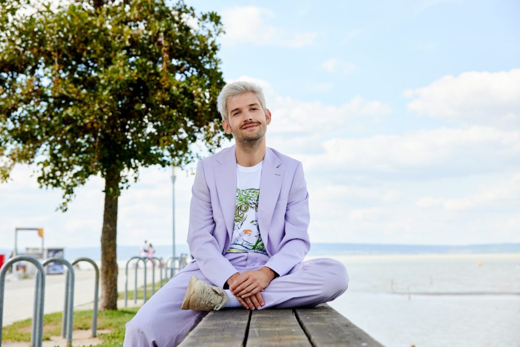 Michael Buchinger in einem flieder-farbenen Anzug am Steg des Neusiedler Sees