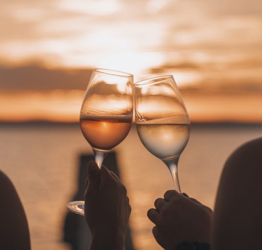 Sicht auf den See und zwei Damen stoßen mit Weingläsern an