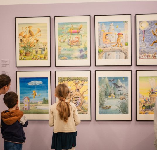 Drei Kinder und eine Frau betrachten acht Bilder von Erwin Moser © Walter Skokanitsch/Kunstmeile Krems