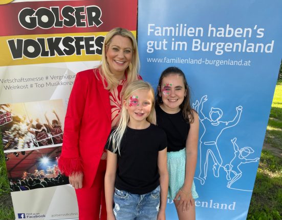 Daniela Winkler steht mit zwei Mädchen vor einem Plakat zum Golser Volksfest