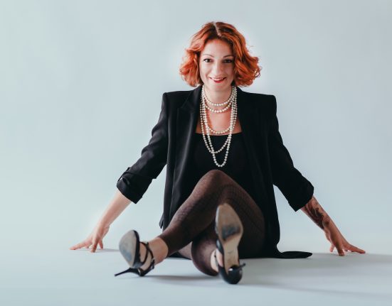 Die Pianistin Maria Radutu sitzt auf dem Boden, die Beine überschlagen und mit aufgestützten Armen. Um den Hals trägt sie mehrere Perlenketten. © Vanja Pandurevic