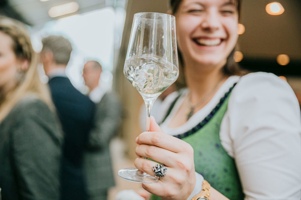 Eine Frau im Dirndl hält ein Weinglas in der Hand