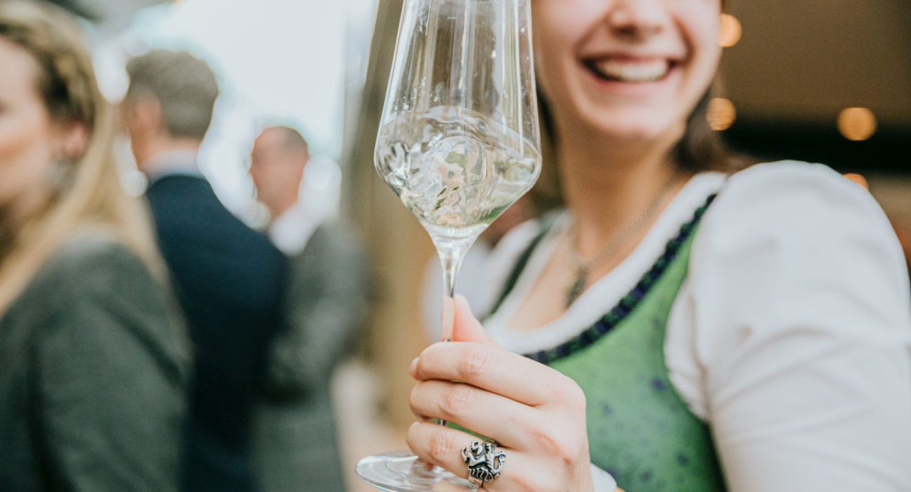 Eine Frau im Dirndl hält ein Weinglas in der Hand