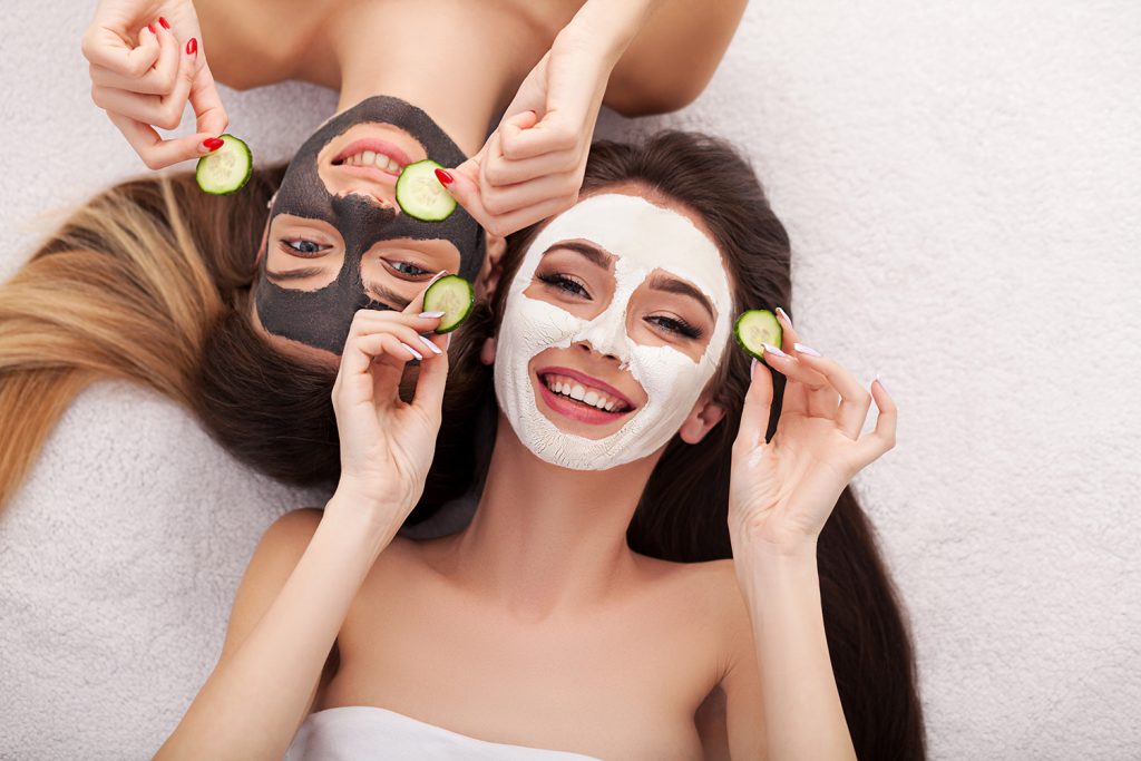 Zwei Frauen mit Gesichtsmasken und Gurken um ihre Haut zu pflegen