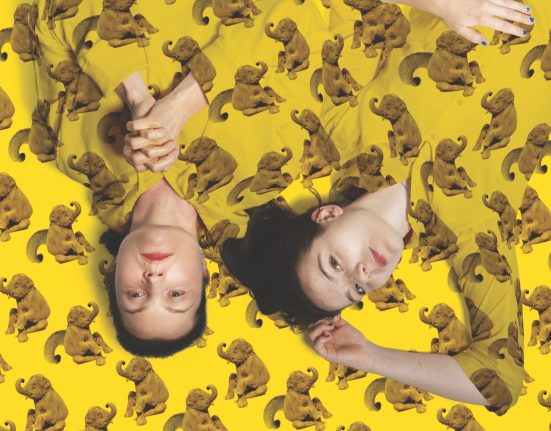 Julia Kreusch und Caroline Baas liegen auf einer gelben Decke mit Elefanten und tragen Hemden aus demselben Stoff. Foto für „Der Menschenfeind“ © Franzi Kreis