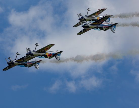 vier Red-Bull Flugzeuge im Himmel während einer Airshow, links fliegen zwei dicht nebeneinander, rechts zwei übereinander