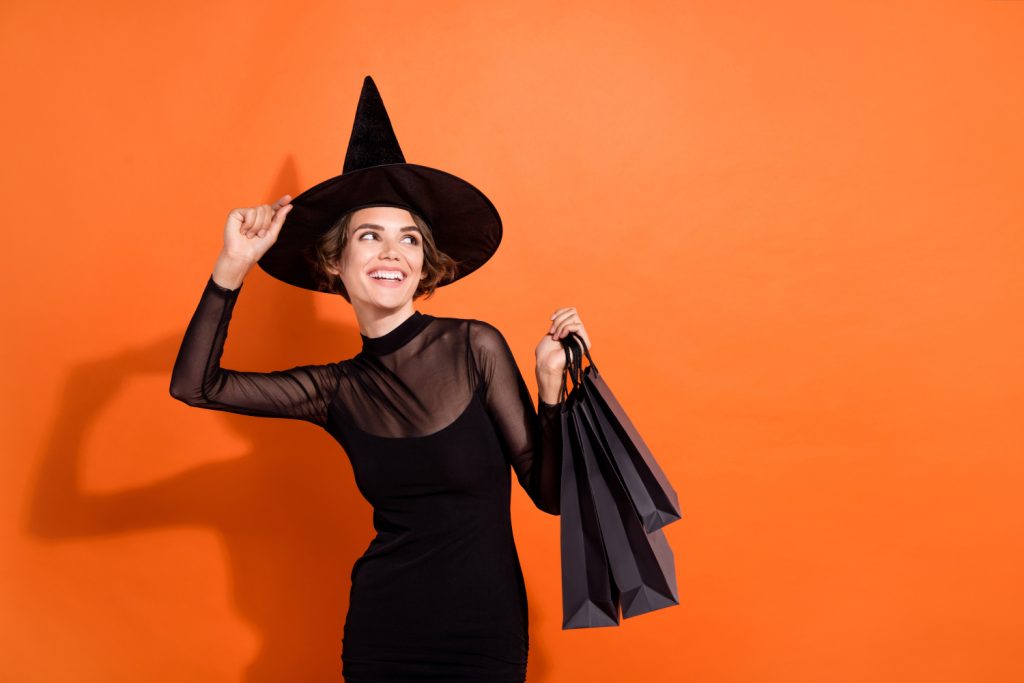 Frau als Hexe verkleidet zu Halloween mit Shoppingbags