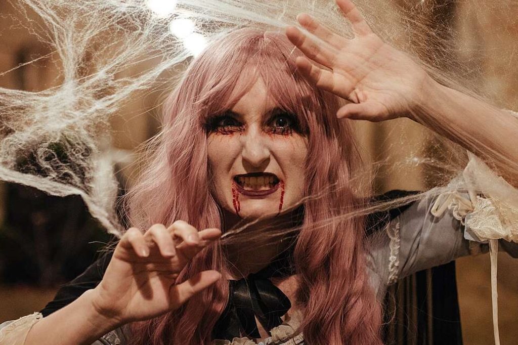Eine Vampirfrau, der Blut beim Mund herausläuft, umgeben von Spinnweben. (Bild zu Halloween-Special) © Schloss_Schoenbrunn_Kultur-_und_BetriebsgesmbH_Michal_Cilc