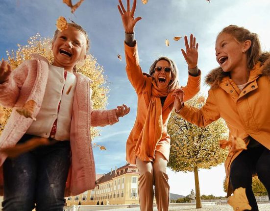 Eine Frau und zwei Mädchen freuen sich vor Schloss Hof, dass das Herbstlaub fällt. © Schloss_Schoenbrunn_Kultur-_und_BetriebsgesmbH_Michal_Cilc