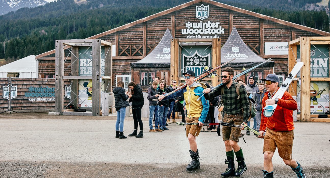 Besucher am Winter-Woodstock der Blasmusik mit Ski und in Lederhosn vor der Mainstage
