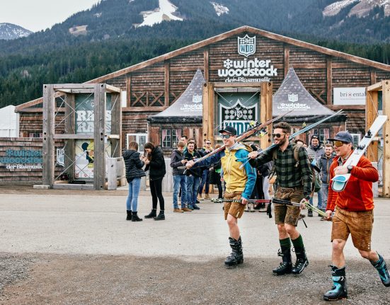 Besucher am Winter-Woodstock der Blasmusik mit Ski und in Lederhosn vor der Mainstage