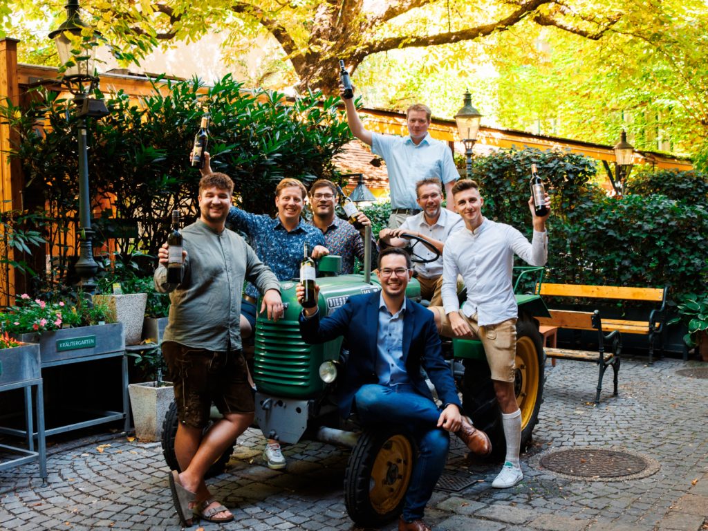 Die glücklichen Nominierten der Schlossquadart Trophy auf einem grünen Traktor sitzend in einem Innenhof auf Pflastersteinen.