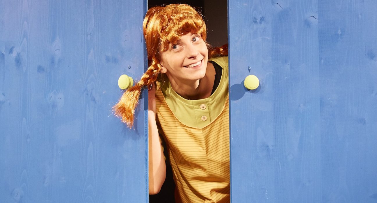 Ein Mädchen mit Zöpfen (Pippi Langstrumpf) schaut bei einer Tür heraus. © Michael Traussnigg