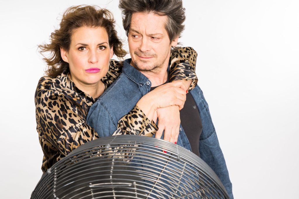 Elena Uhlig und Fritz Karl stehen sich umarmend vor einem Ventilator. © Michael Kammeter
