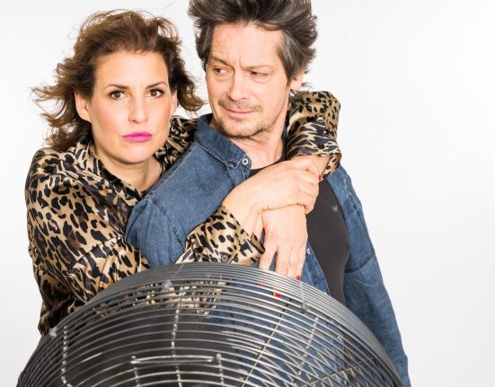 Elena Uhlig und Fritz Karl stehen sich umarmend vor einem Ventilator. © Michael Kammeter