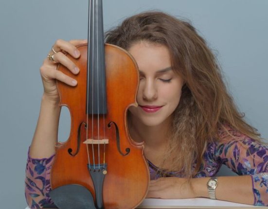 Sabina Bakholdina stützt sich mit dem linken Arm auf und hält im linken ihre Geige. Sie hat die Augen geschlossen. (KLANGherbst) © Sabina Bakholdina
