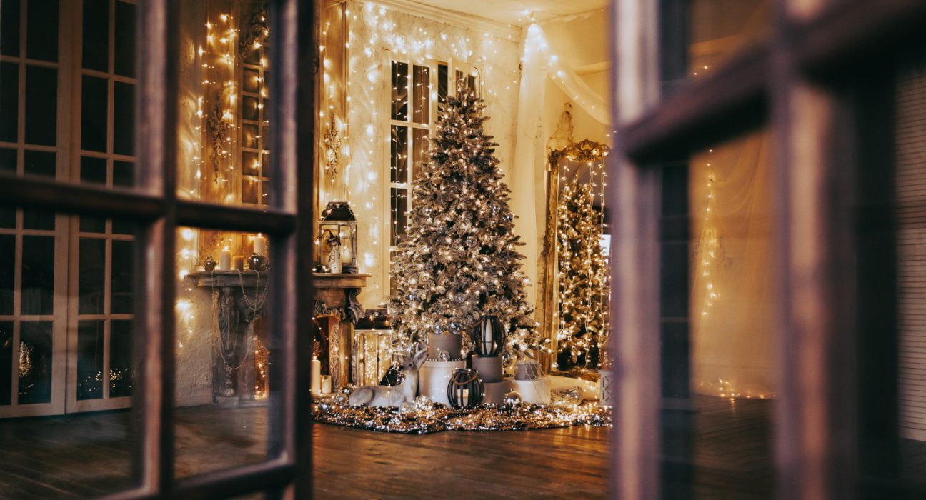 Sicht auf ein weihnachtlich geschmücktes Zimmer mit Weihnachtsbaum und Lichterketten