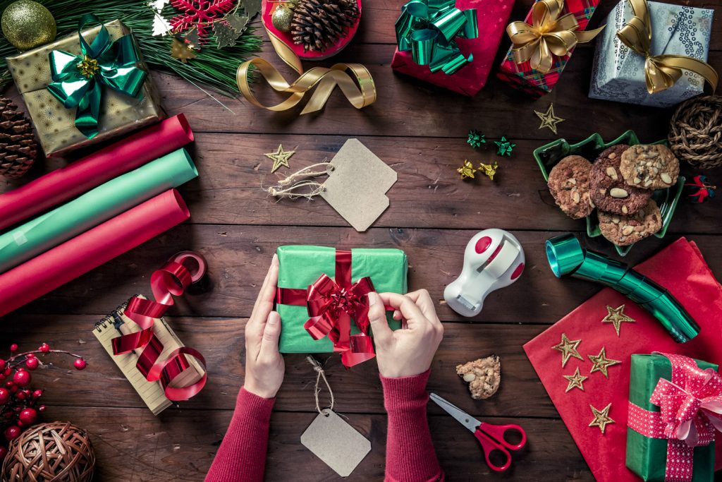 Weihnachtsgeschenke am Tisch platziert mit Scheren, Geschenksbändern und Schleifen.