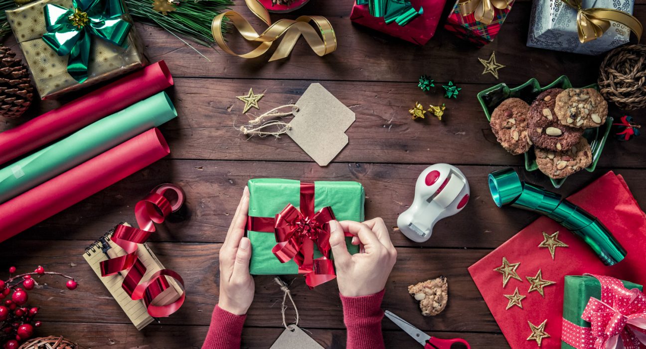 Weihnachtsgeschenke am Tisch platziert mit Scheren, Geschenksbändern und Schleifen.