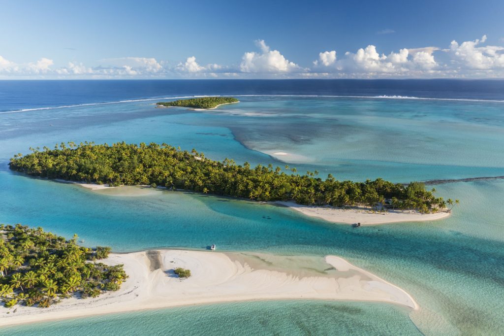 Drohnenaufnahme von One Foot Island voller Palmen umgeben von türkisem Wasser