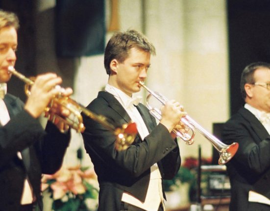 Drei Trompetenspieler im Frack in einer Kirche