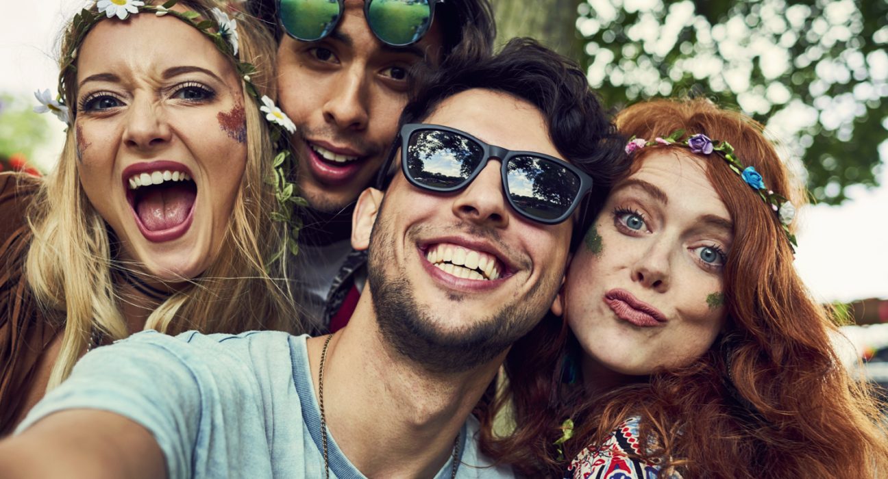 Zwei Frauen und zwei Männer machen mit Festival-Klamotten ein Selfie.