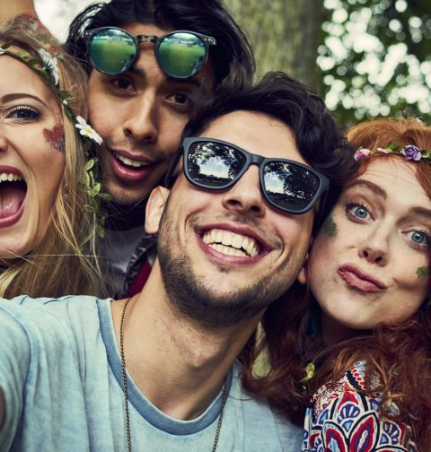 Zwei Frauen und zwei Männer machen mit Festival-Klamotten ein Selfie.