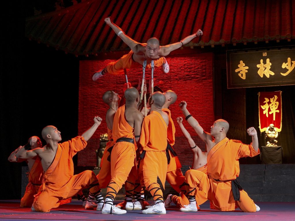 Shaolin Mönche in Action: Mönch balanciert mit seinem Körper auf ein paar wenigen Speerspitzen.