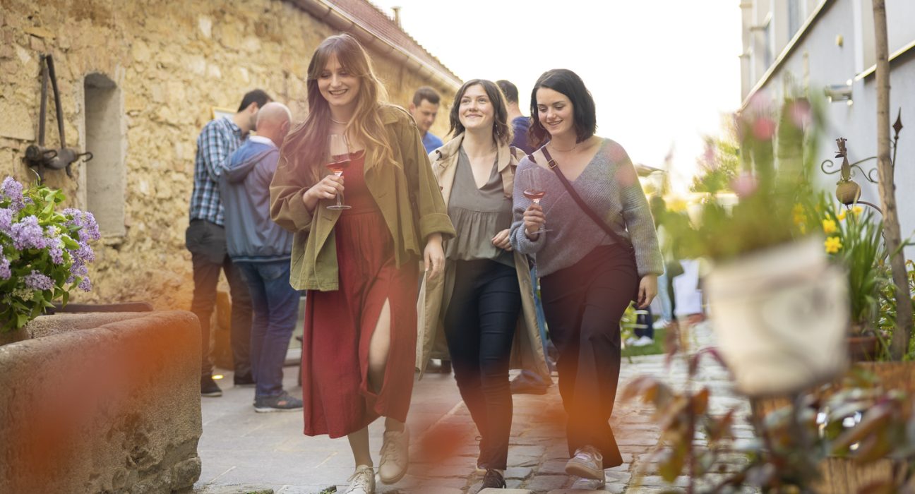 3 Frauen schlendern mit Weingläsern in der Hand durch Gassen in Jois