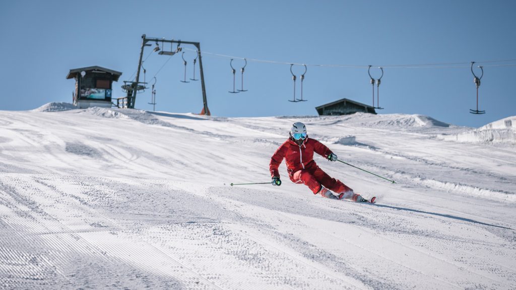 Skifahrer beim Carven auf präparierter Piste im Skigebiet Berchtesgaden, Schlepplift im Hintergrund