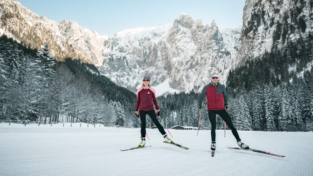 Paar beim Langlaufen vor verschneiten Bäumen und Bergpanorama in Berchtesgaden