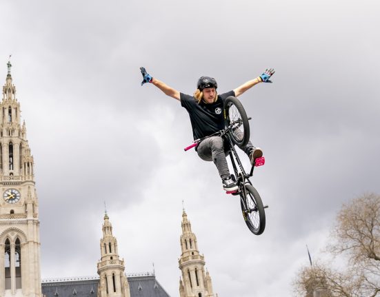 Sportler springt auf BMX freihändig in die Luft