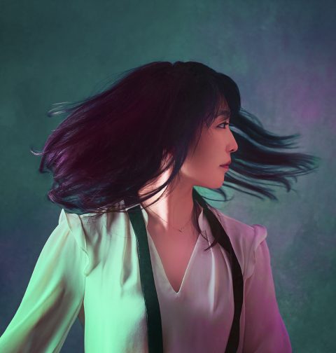 Claire Huangci seitlich vor einem grün-violett-schimmernden Hintergrund