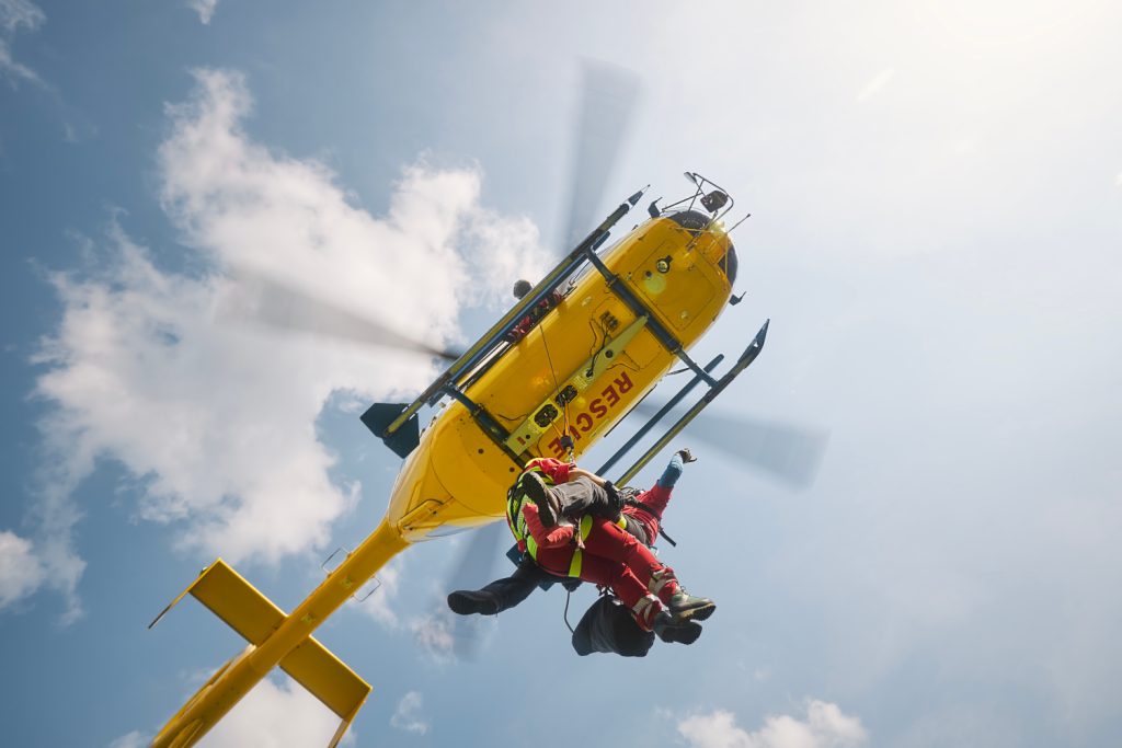 Zwei Notärzte hängen an einem Seil unter einem Notarzt-Hubschrauber im Einsatz