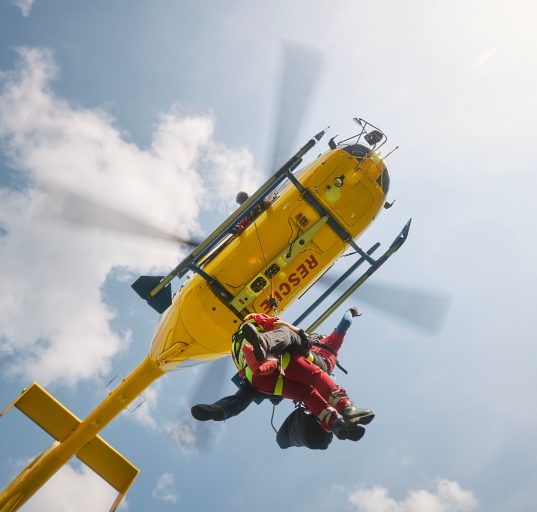 Zwei Notärzte hängen an einem Seil unter einem Notarzt-Hubschrauber im Einsatz