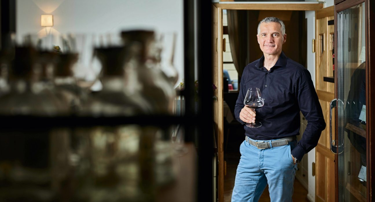 Hermann Botolen mit einem Glas Wein in der Hand im Weinkeller