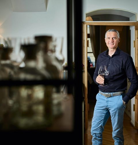Hermann Botolen mit einem Glas Wein in der Hand im Weinkeller